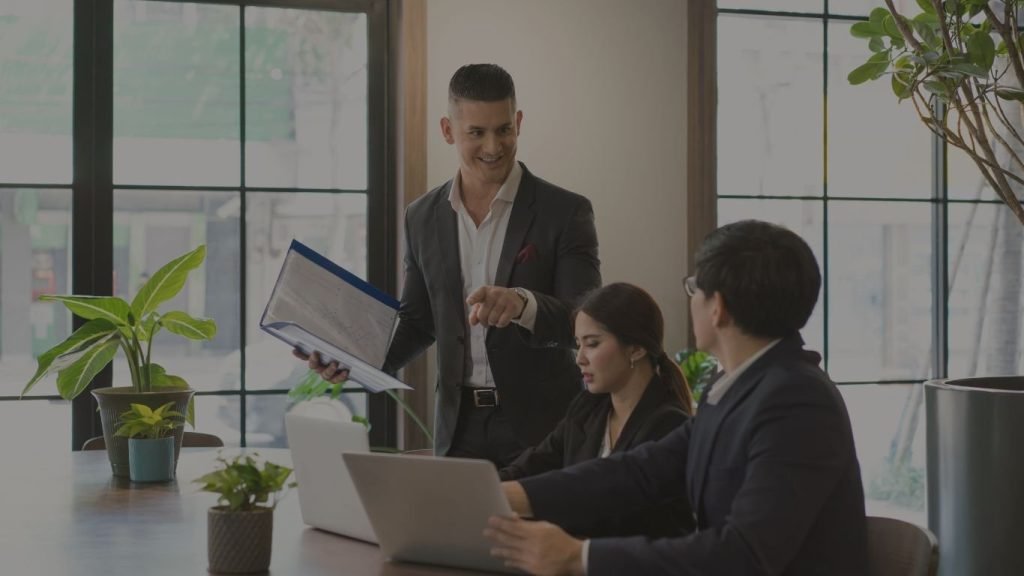 Hombre capacitando a dos de sus compañeros en el trabajo