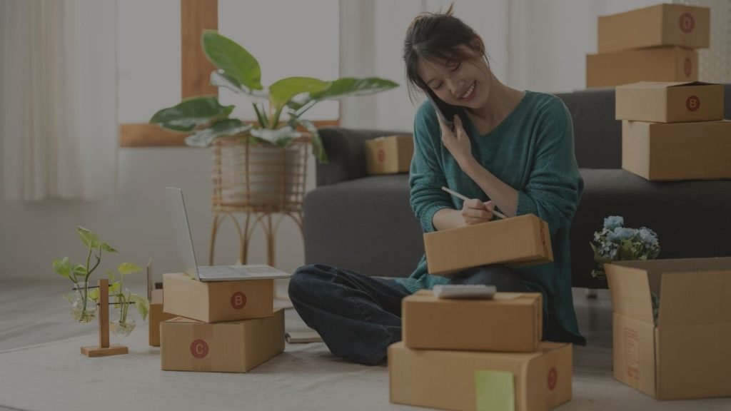 Emprendedora al teléfono con paquetes de productos por enviar